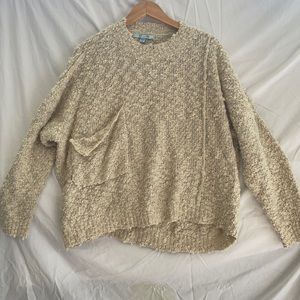 Tan sweater. Pocket sewn to look ripped.